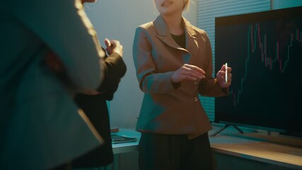 Aufkleber - Businesswoman is gesturing while explaining data or a strategy to a colleague using a large screen displaying a candlestick chart