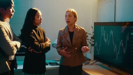 Poster - Businesswoman is giving a presentation about the stock market to her colleagues in an office setting. She is pointing at a monitor with a graph on it