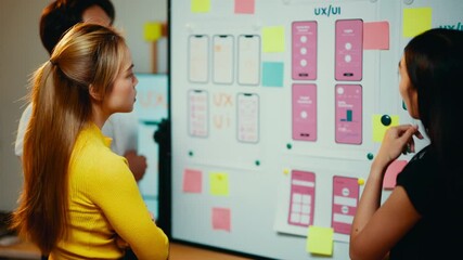 Poster - Ux/ui designers are working together in the office. They are discussing the user interface of a mobile application using wireframes and sticky notes
