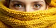 © Pluto - A single, curious eye peeks out from behind a warm, yellow knitted scarf, hinting at a hidden face and a tale waiting to be told.
