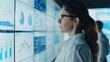 © Vilaysack - A businesswoman wearing glasses analyzes financial charts and graphs displayed on multiple digital screens in an office environment.