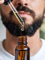 bearded man using beard hair grooming cosmetic serum oil. natural beauty facial skincare treatment. 