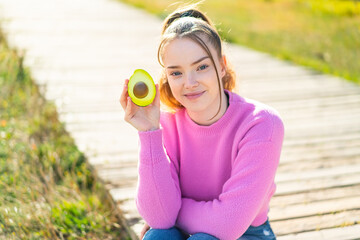 Poster - Young pretty girl at outdoors holding an avocado