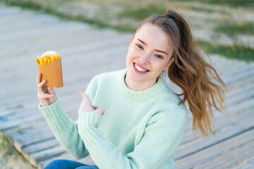 Wall Mural - Young pretty girl holding fried chips at outdoors and pointing it