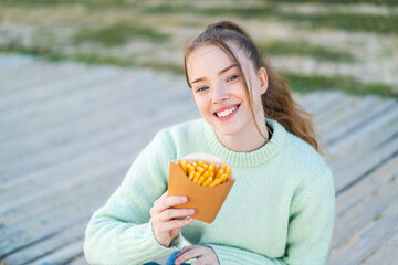 Sticker - Young pretty girl holding fried chips at outdoors with happy expression