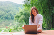 © Farknot Architect - Portrait image of a woman using and working on laptop computer while sitting on balcony with a beautiful nature view