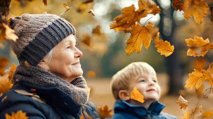 Elderly woman enjoys a joyful moment with her grandson as they watch autumn leaves fall in a serene park setting