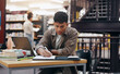 © LuxeShutter24/peopleimages.com - African, man and student writing in library for research information, university thesis and study schedule. Male person, laptop and reading for education knowledge, history exam and project planning