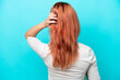 © luismolinero - Young Russian woman isolated on blue background in back position and thinking