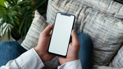 close up shot two hand man in white shirt holding mobile smartphone with blank white screen background while resting on the sofa in living room at home. watching on the phone