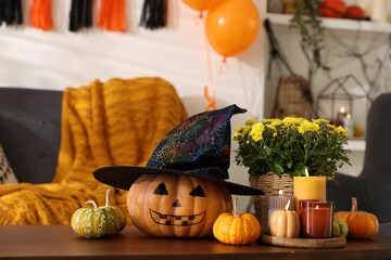 Sticker - Burning candles, flowers and pumpkins on table in room decorated for Halloween