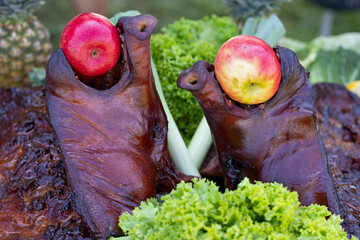 Two heads of roasted suckling pigs from the barbecue, each with an apple in their mouth.