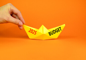 Planning 2025 budget new year symbol. Concept words 2025 Budget on beautiful yellow paper boat. Beautiful orange paper background. Businessmen hand. Business 2025 budget new year concept. Copy space.