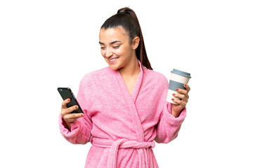 Wall Mural - Young woman in a bathrobe over isolated chroma key background holding coffee to take away and a mobile