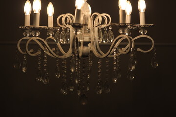 Poster - A chandelier with five lit candles provides warm and cozy atmosphere.