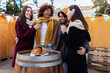 © Xavier Lorenzo - Happy group of young friends drinking hot drink at christmas market on winter. Friendship and vacation concept.