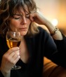 © Elena - A woman with glass of whiskey, sits with her eyes closed, holding her head with one hand. Thinking about problem at work or relationship problems, feeling desperate and depressed, alcohol addiction