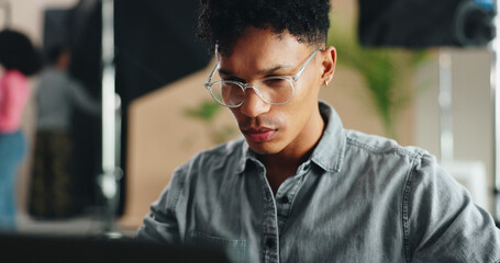Poster - Man, photographer and glasses with laptop for production, film making or design at studio. Young, male person or producer working on computer for content creation, research or media app at workplace