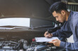 © KMPZZZ - Auto check, car service shop concept. Automobile repairman writing job checklist on clipboard, mechanic checking engine to estimate repair machine, inspecting maintenance by engineer at vehicle garage