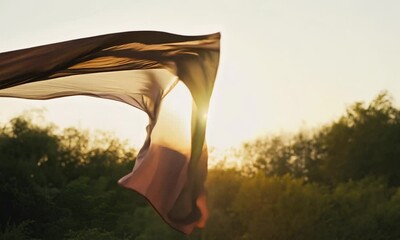 Wall Mural - brown fabric dances in sunset light against lush green trees.