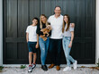© Austockphoto - Happy family standing outside in front of black garage door with pet dog