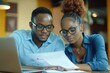 © Art_You - Young African American couple working together at a desk reviewing documents and using a laptop in a collaborative effort