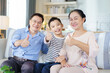 © DG PhotoStock - Asian family with father, mother, and son staying in living room together.
