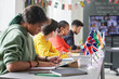 © Mediaphotos - Side view at diverse group of students sitting at table with country flags during international conference in school