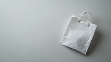 Poster - A neatly folded white plastic shopping bag rests flat against a smooth light-gray surface, highlighting its glossy texture. Empty space on the right allows for additional text or design