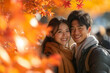 © Jirut - A happy young Asian couple enjoying an autumn day, surrounded by the vibrant colors of falling maple leaves.