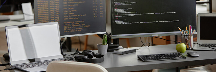 Fototapete - Website header shot of programmer desk setup with laptop and multiple computer screens displaying source code programming at office workplace