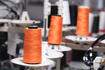 Poster - Spool of thread on an industrial sewing machine in a garment factory, industrial textile background, sewing factory, clothing manufacturing