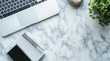 Clean and modern workspace setup with laptop, smartphone, and notebook on marble background, offering ample copy space for design or text