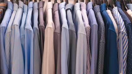 Wall Mural - A row of blue and white shirts hanging on a rack. The shirts are neatly folded and arranged in a row