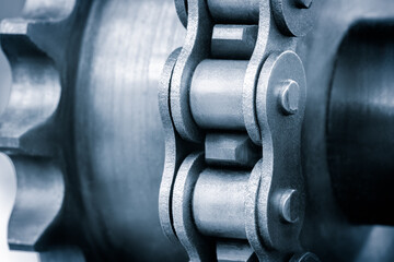 Poster - A chain is shown in a close up. The chain is made of metal and has a silver color. The chain is connected to a gear and is in motion. Concept of movement and mechanical energy