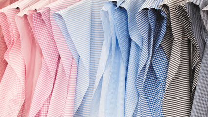 Poster - A row of patterns for shirts in different colors and patterns. The patterns hang on a hanger in a shirt factory