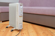 © Kristina - oil heater stands on the floor near the sofa. no people, empty room, copy space. heat saving, heating season concept