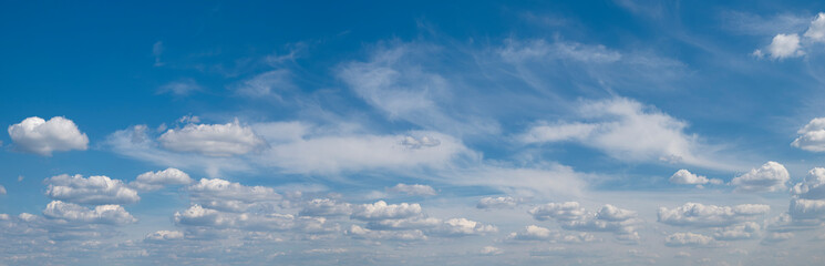 Poster - The sky is blue and filled with clouds. The clouds are scattered throughout the sky, with some closer to the ground and others higher up