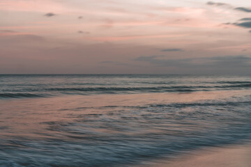 Soft waves rolling in under a pastel-colored sky at dusk, abstract seascape