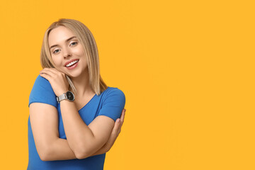 Wall Mural - Young woman hugging herself on yellow background