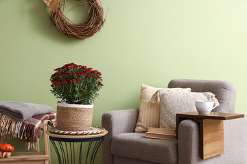 Wall Mural - Interior of stylish living room with armchair and autumn flowers on coffee table