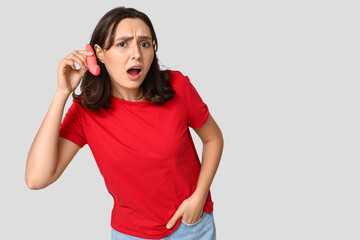 Poster - Emotional young woman with vibrator on grey background