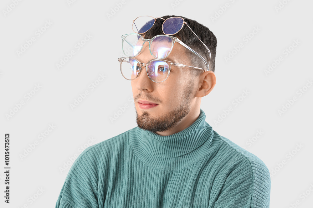 Young man in different eyeglasses on light background, closeup