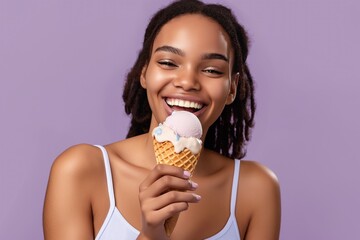 Young African-American woman with dreadlocks holds waffle cone with ice cream on lilac background. Woman smiles, dressed in white tank top, with vibrant attire.