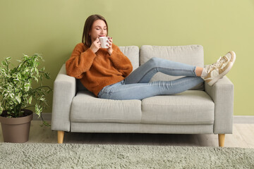 Canvas Print - Young woman drinking tea on sofa at home