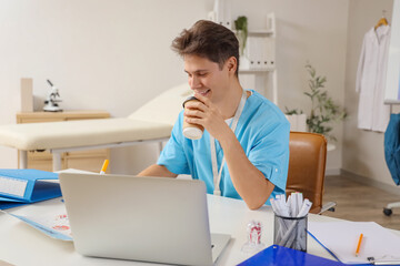 Sticker - Male medical intern with coffee cup studying at table in clinic