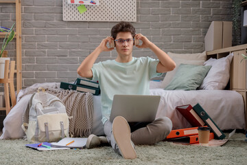 Canvas Print - Male medical intern with headphones and laptop studying in bedroom