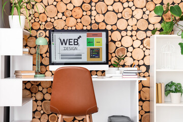 Poster - Web designer's workplace with computer near wooden wall in office