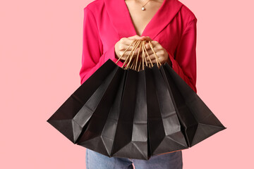 Young woman with shopping bags on pink background. Black Friday Sale