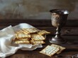 © Y_Malashkevych - Passover celebration table with matzo crackers and ornate silver goblet on rustic wooden surface, religious holiday concept